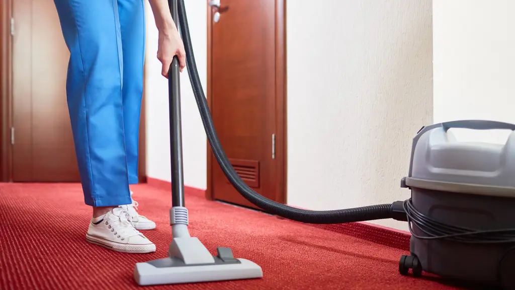 Reinigungskraft saugt den Teppich in einem Hotelflur